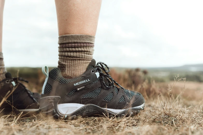 a closeup of the legs and the upper part of a person's foot standing in dry grass with their feet hanging down