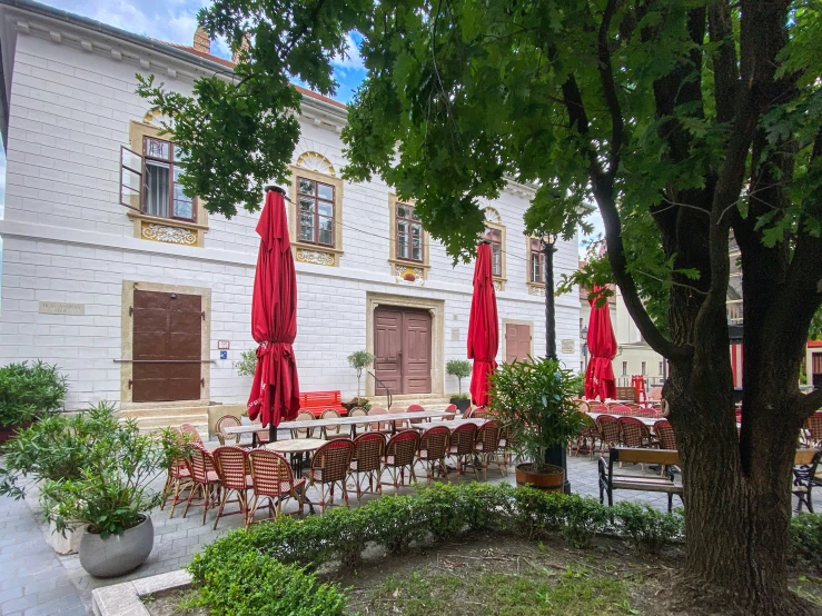 a restaurant has red umbrellas and red tables in a courtyard