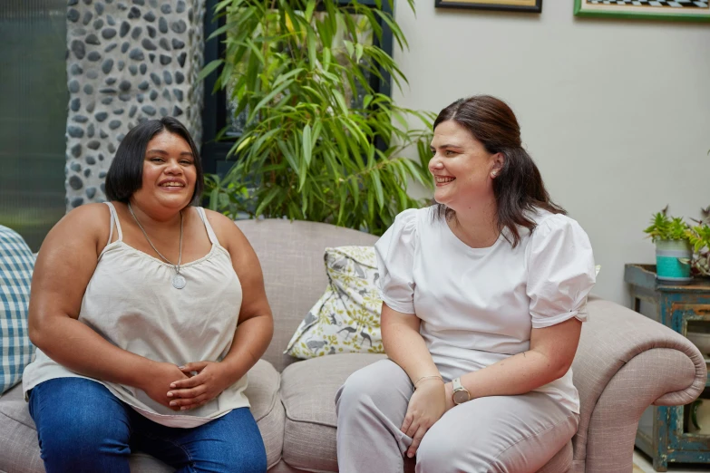 two women smiling together on a sofa