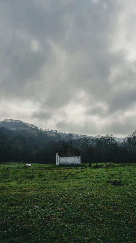 the view from across the field shows a barn and mountains