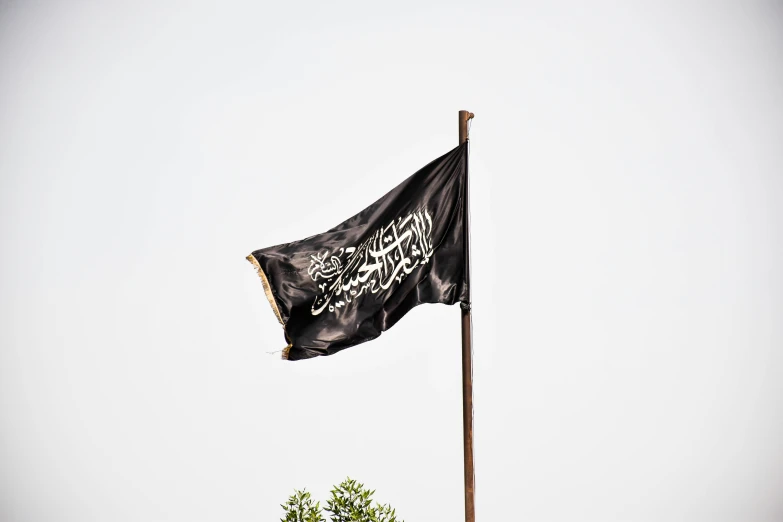 a black flag flies in the wind while on a pole