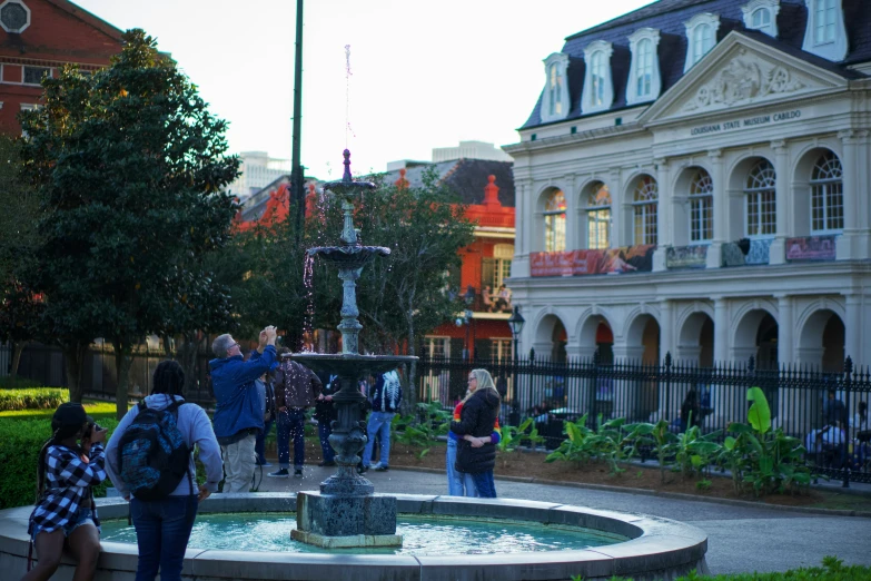 tourists are around the fountain at sunset time