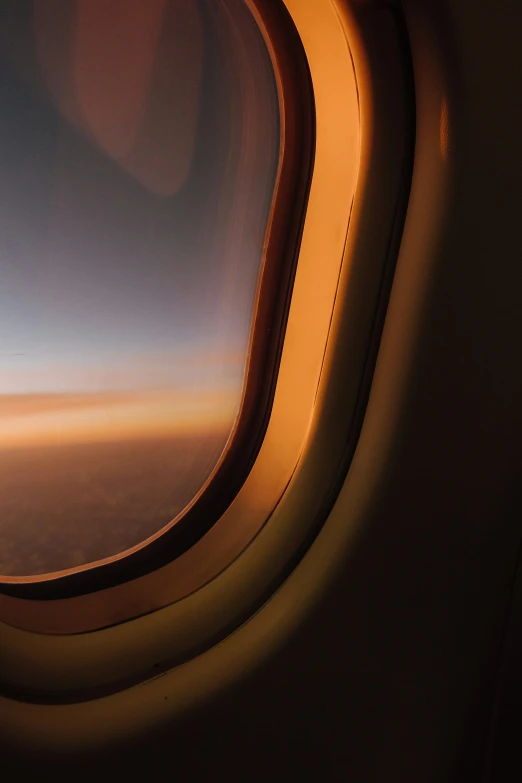 the window of an airplane during flight with a blurry picture of the wing and some sky