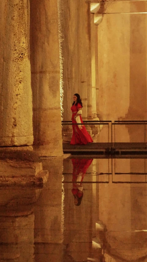 a woman in a red dress walking on the water in a large area