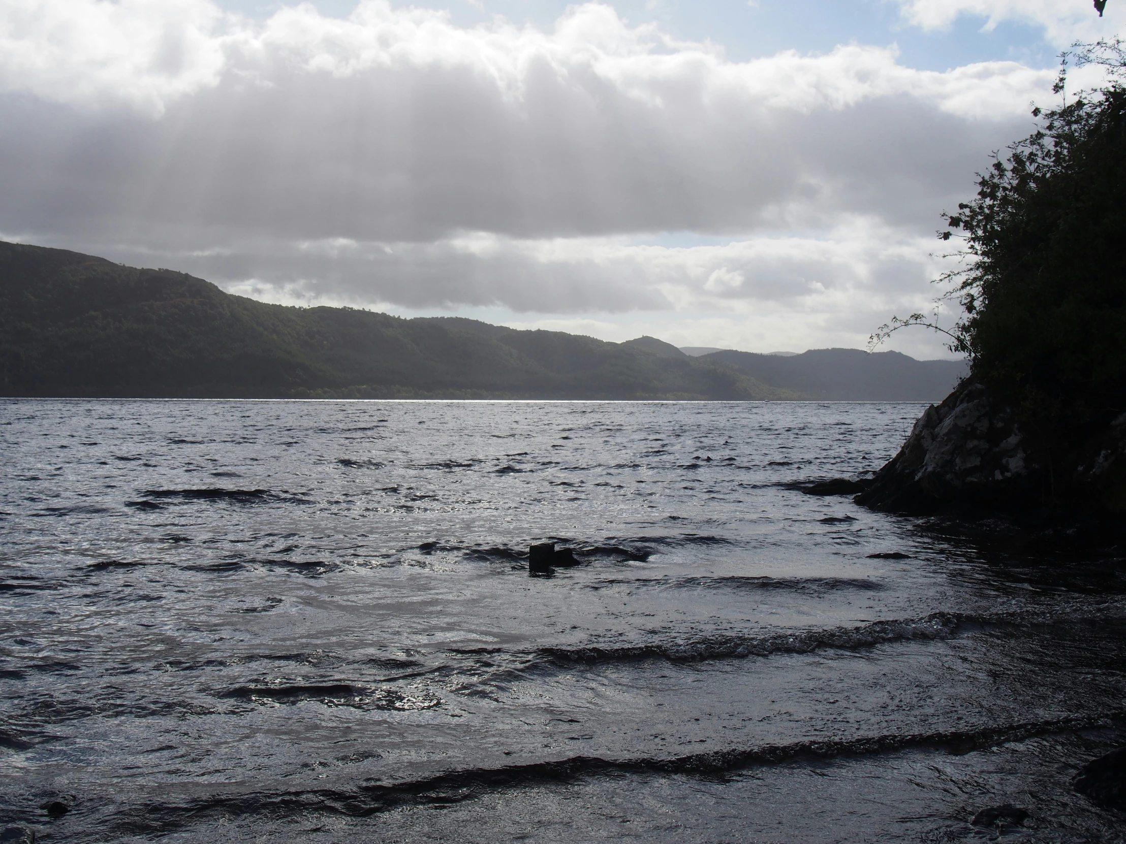 water in the ocean, with rocky shoreline under a cloudy sky