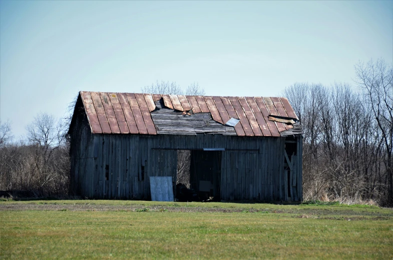 a barn with a metal roof in the middle of a field