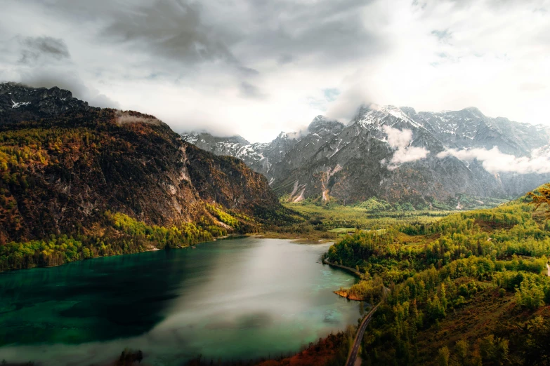 an aerial view of a green lake with mountains in the background