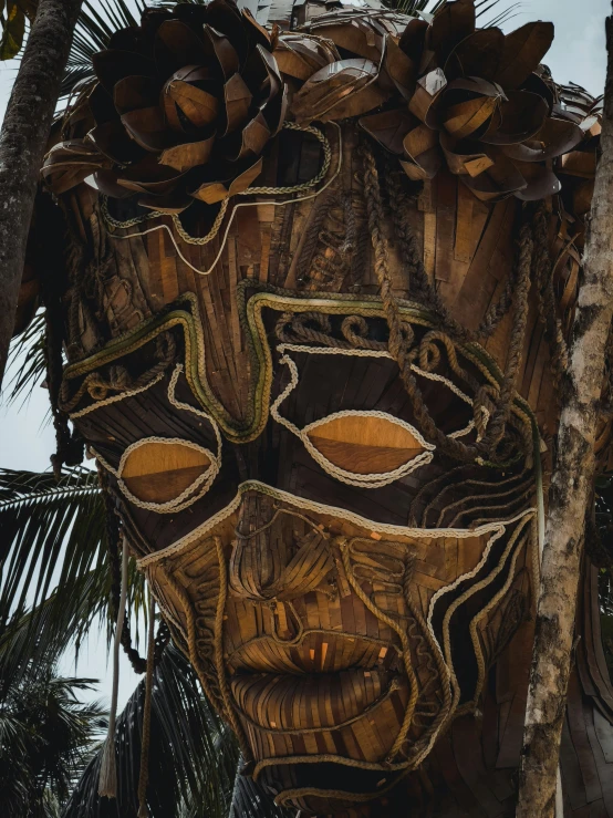 a wooden mask sitting by some trees