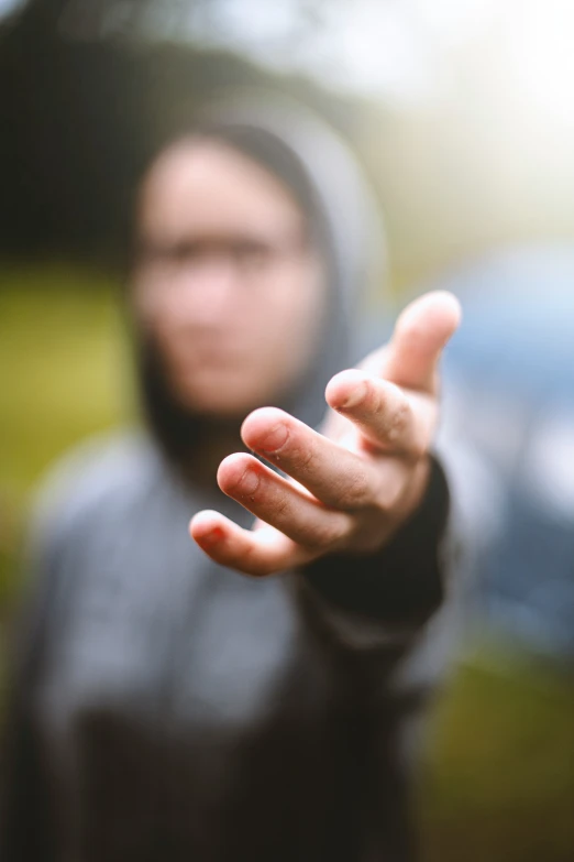 a person wearing a hoodie holding up their hand