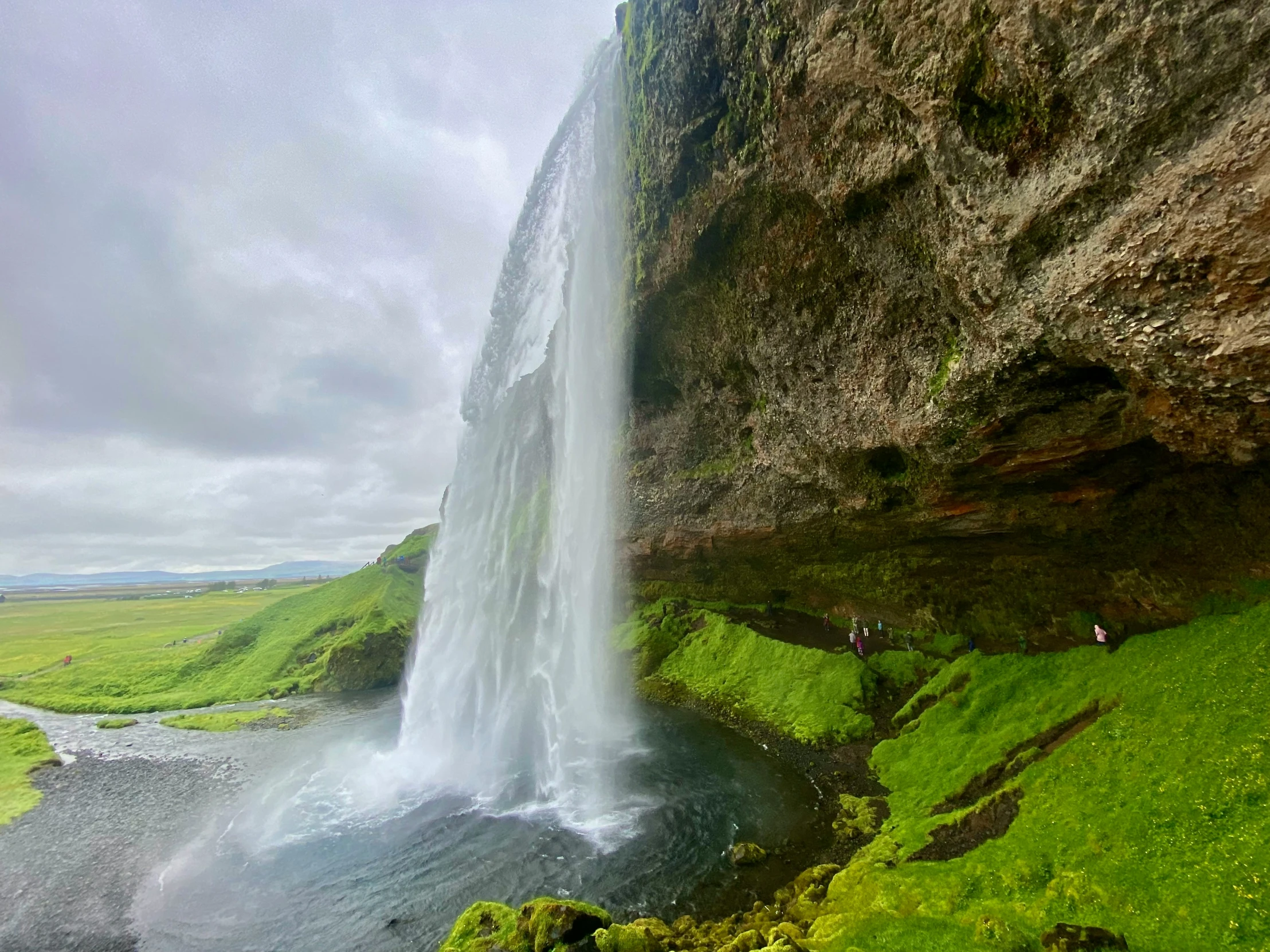 a large waterfall near a field with green grass