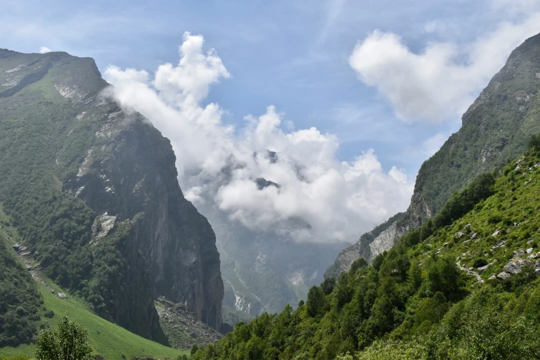 mountains are dotted with clouds, grass and trees