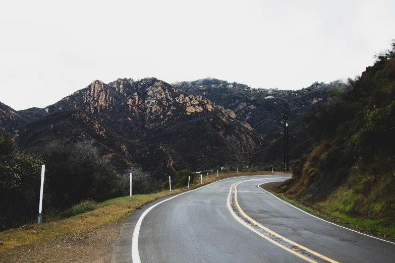 a winding road in the mountains with one car coming up the right