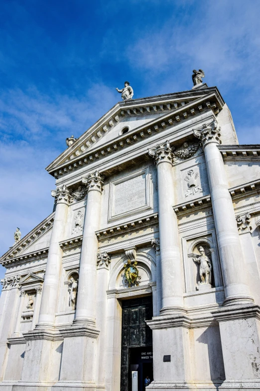 an elaborate looking white stone building with statues on it