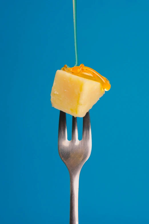 there is a fork with a block of cheese on it