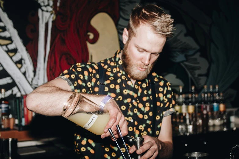 man making a drink at a bar while holding a liquor glass