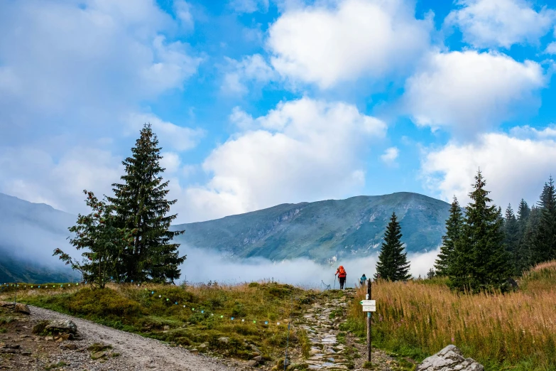 person hiking on the trail in mountains above clouds