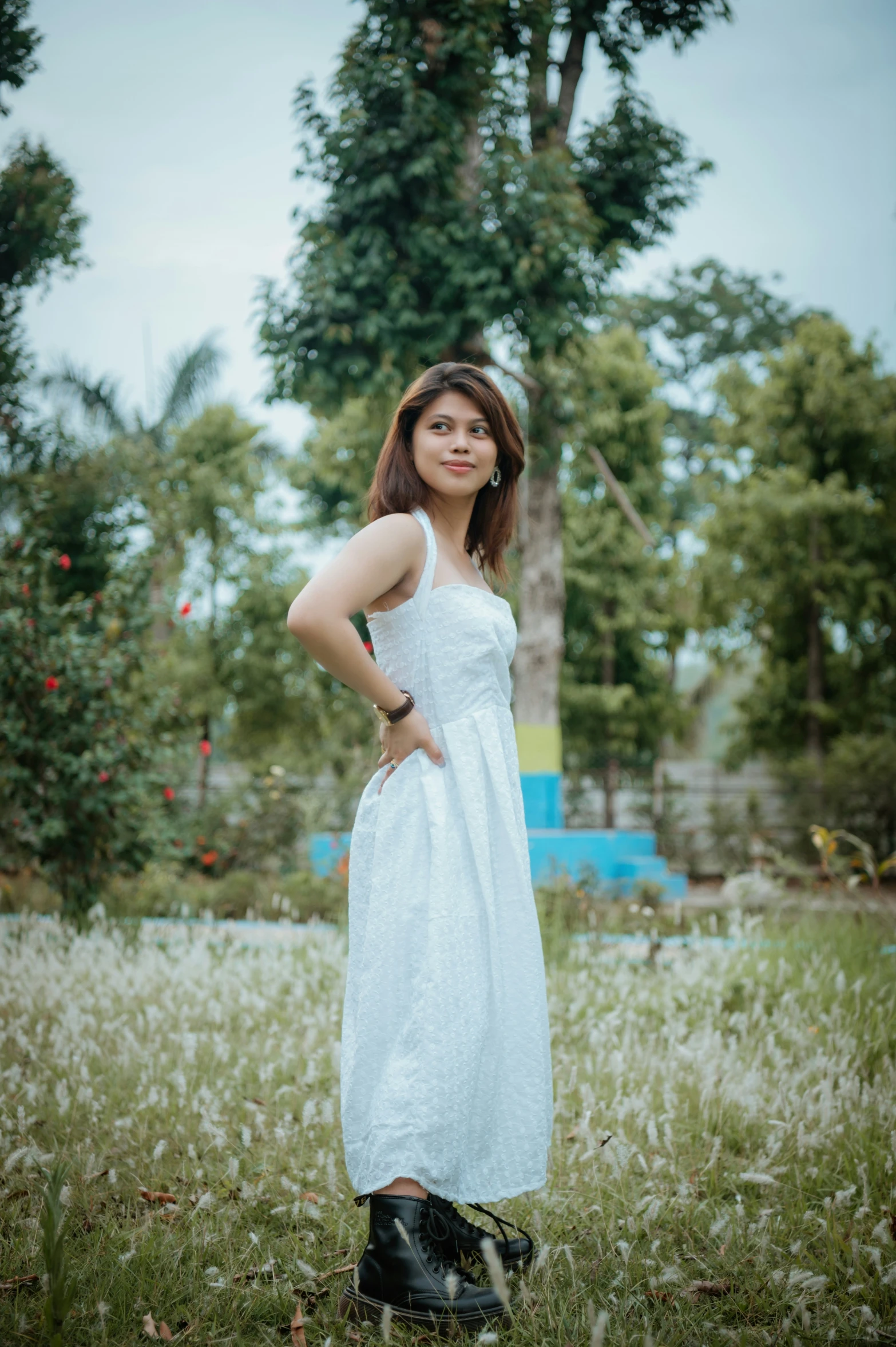 a woman is in a dress posing with a tree in the background