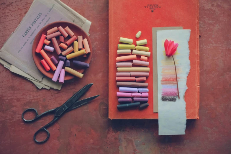 a book, paper and scissors that are laying on the table