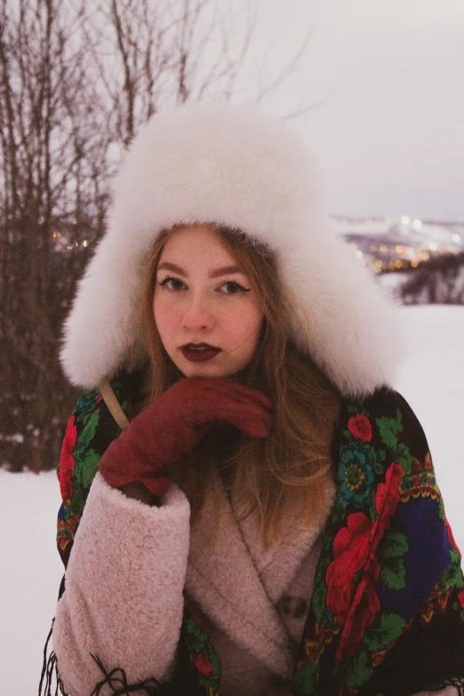 a young woman standing in the snow wearing a hat