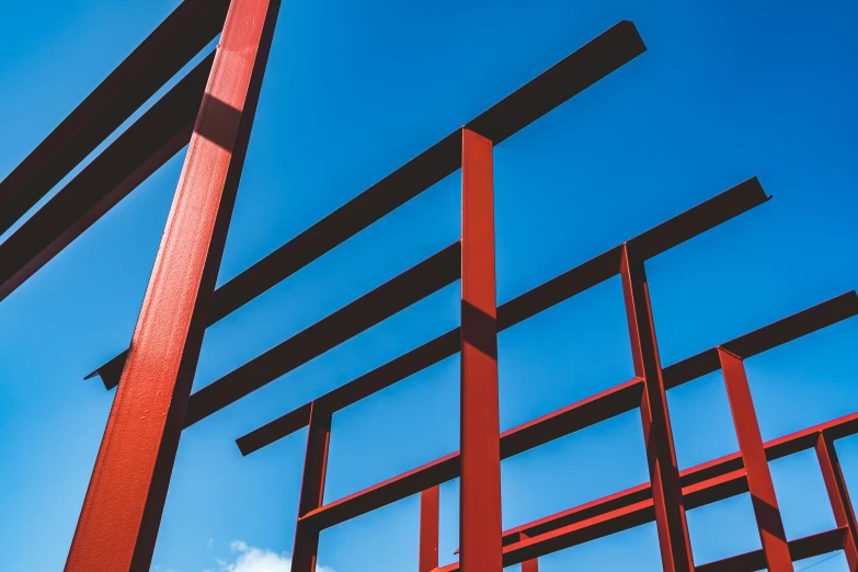 an abstract po of red metal structures against a blue sky