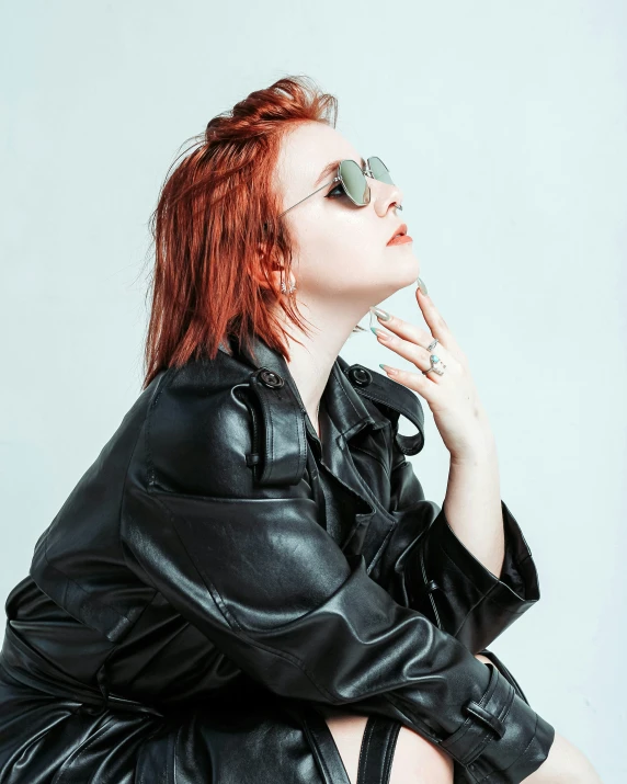 a woman wearing leather clothing and sunglasses sits