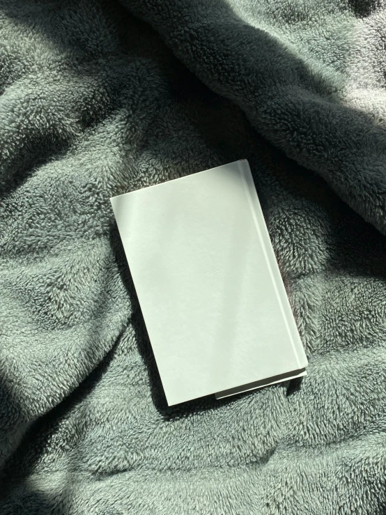 a book laying on a blanket on the bed