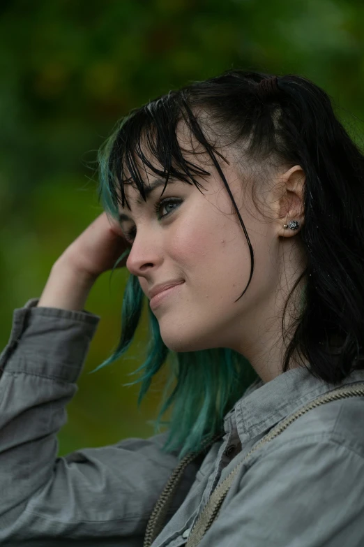 a woman with green hair looks into the distance