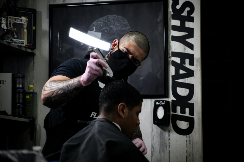 a man in a barber shop getting a cut with a black mask
