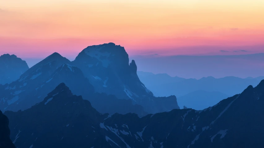 birds flying above the top of mountains during a sunset