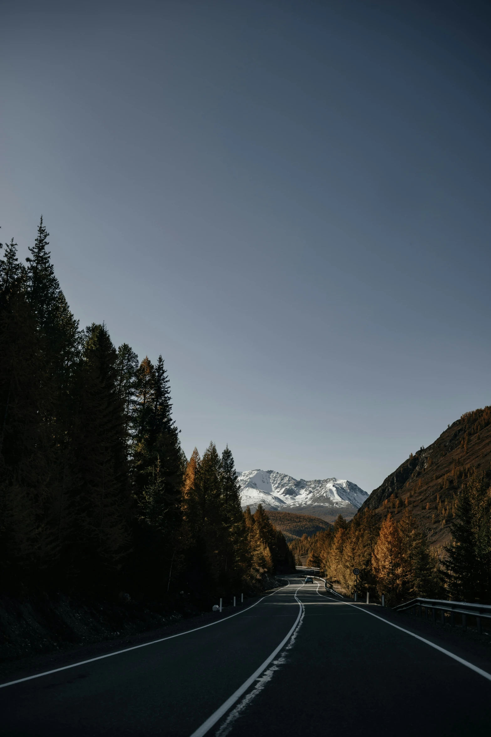 an empty road surrounded by mountains under a blue sky