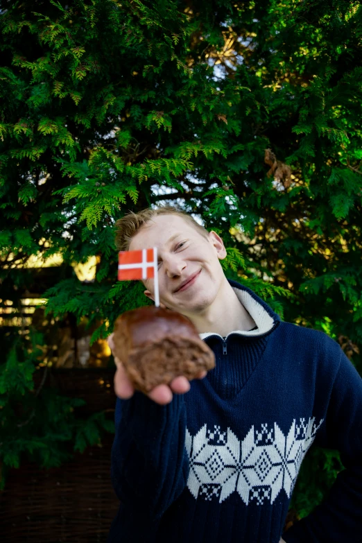 a young man holding a doughnut and an flag in the background