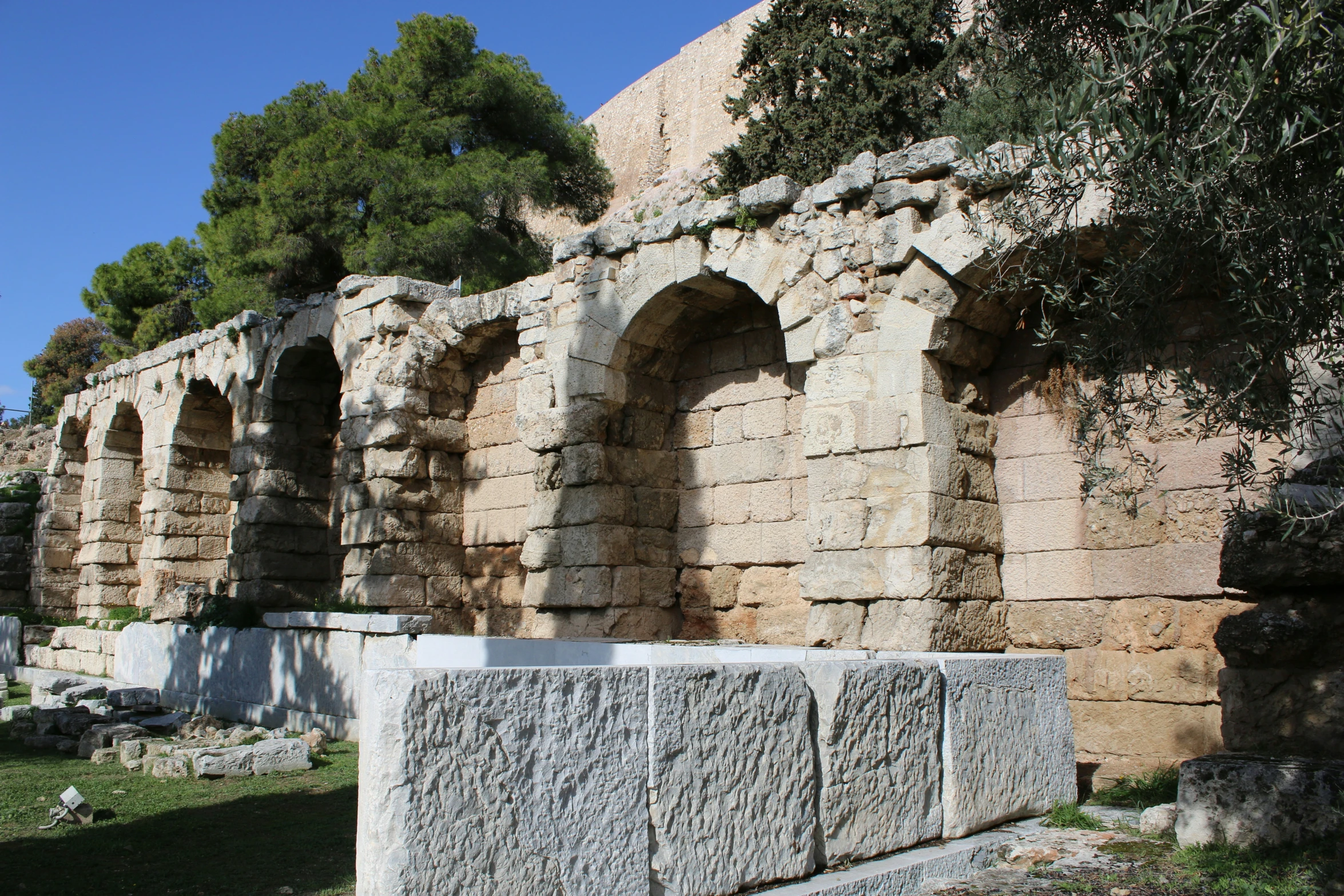 a small wall near a large cement block with trees in it