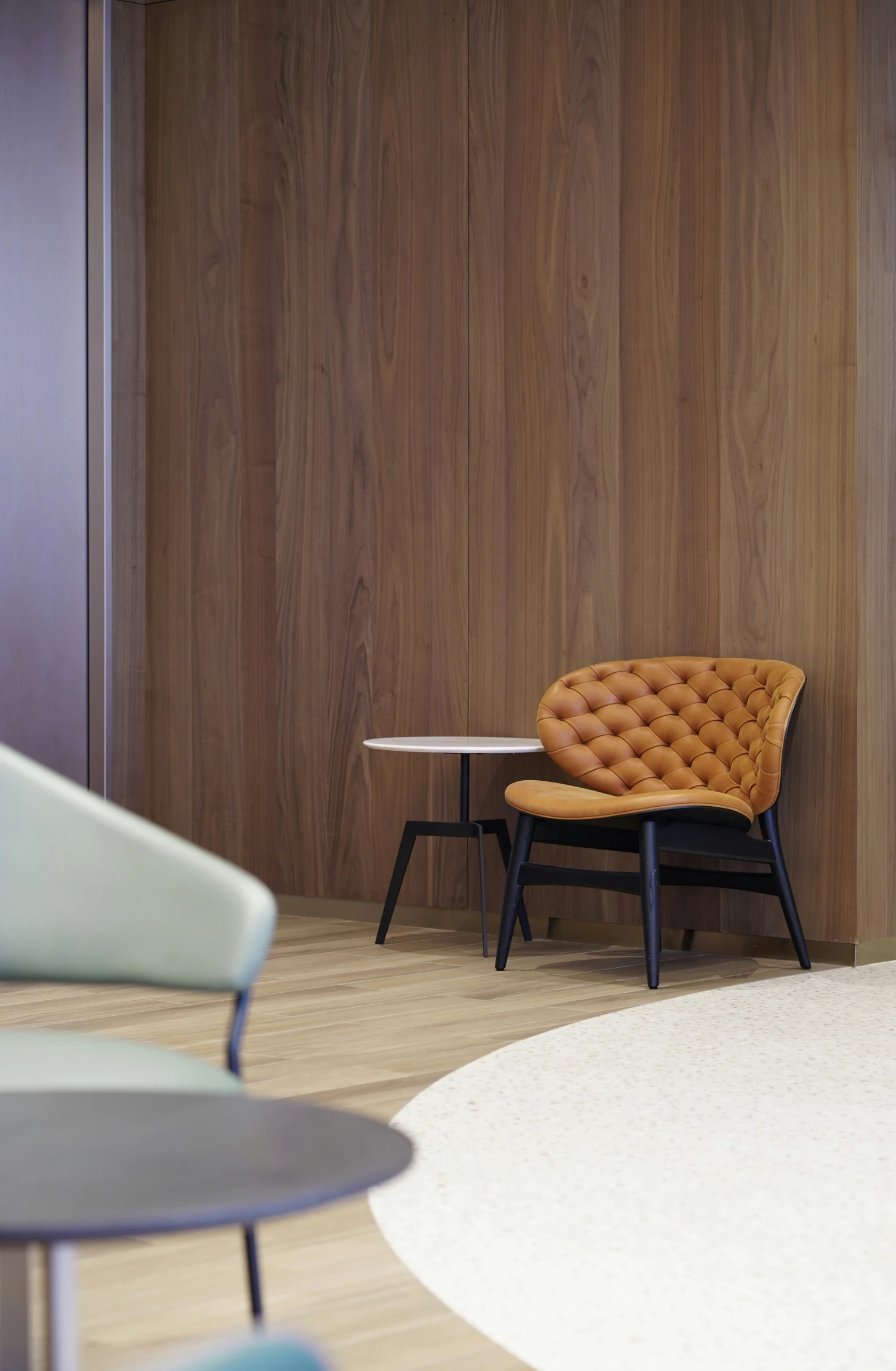 a brown chair on a white rug near some tables