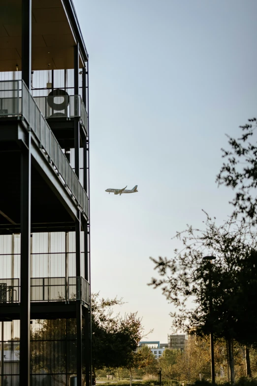 an airplane flying over a building that's next to trees