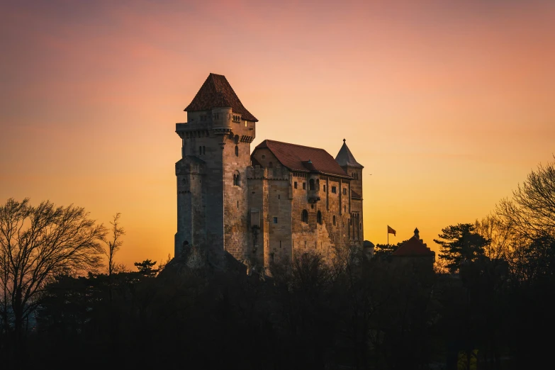 the silhouette of a medieval castle under an orange sky