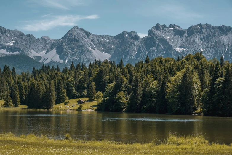 a beautiful mountain range next to a lake surrounded by pine trees