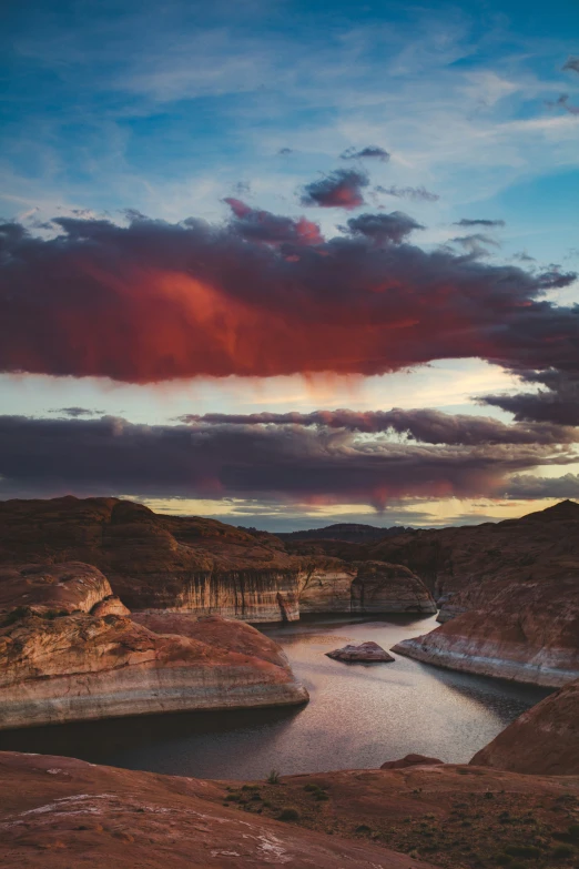 a large canyon with a body of water below a cloudy sky