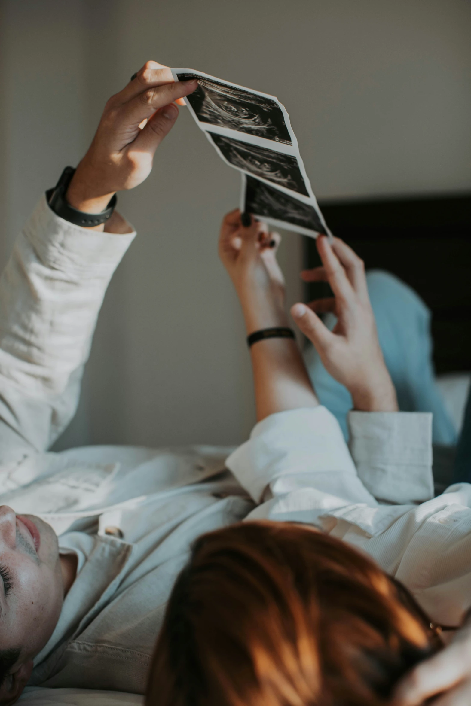 a  laying in bed holding up a cell phone