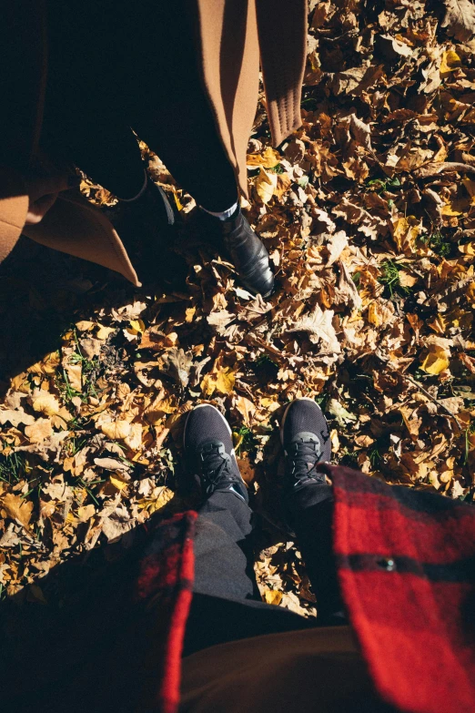 two people standing next to each other on a leaf covered ground