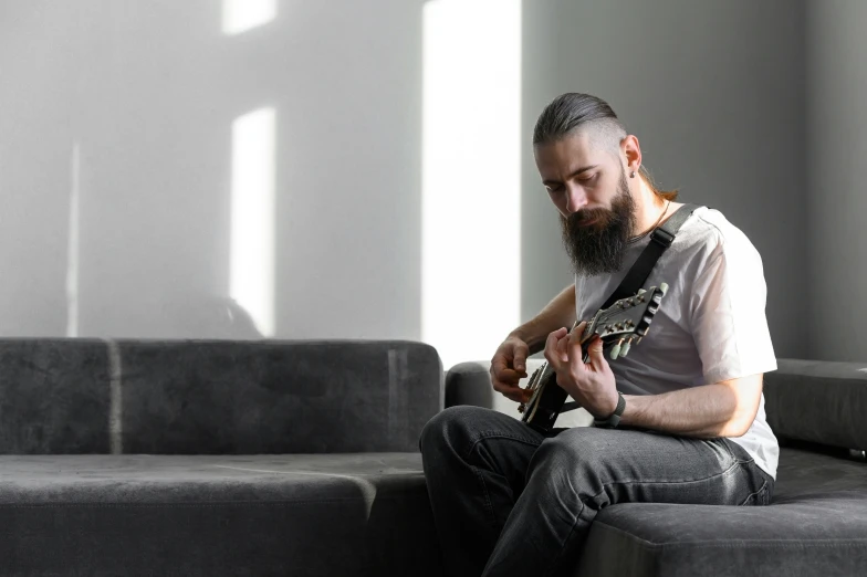 a man sits on a sofa playing a guitar