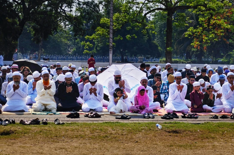 a group of people gathered on a sidewalk near a park