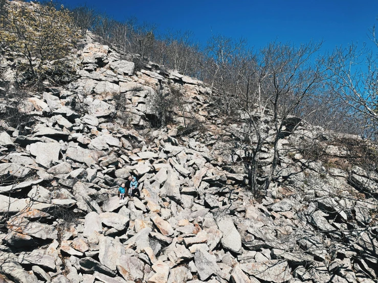 a blue hiker hiking up a rocky hillside