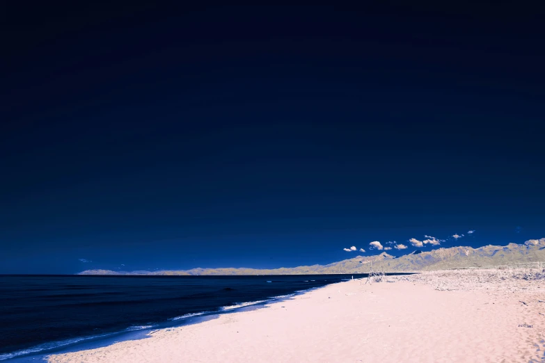 a lone person surfing on a small wave covered beach