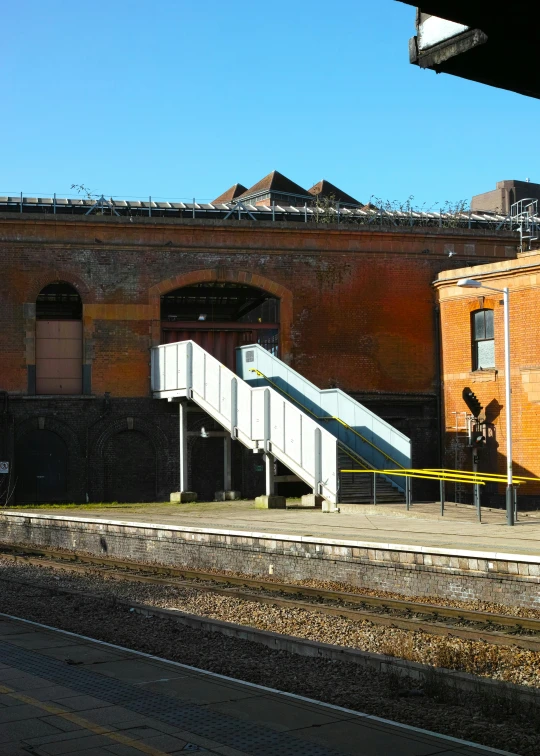 an orange train car sitting on a train track near a train station