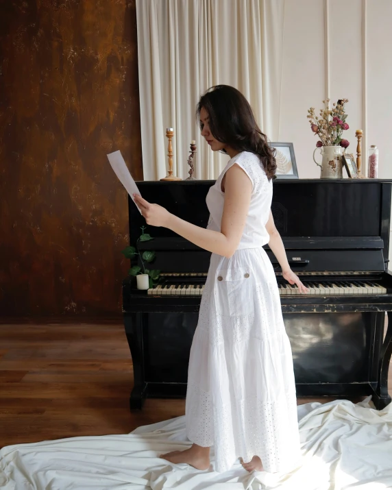 a woman in a white dress standing near a piano