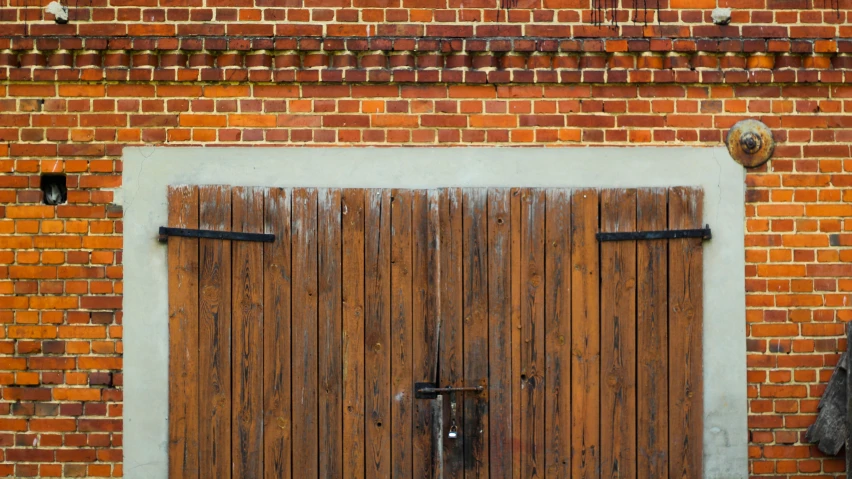 a brick building with two brown doors and two coats hanging on the door