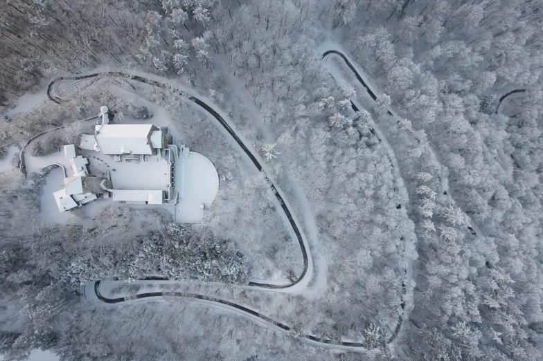 a snow covered rural landscape with a road and an old building