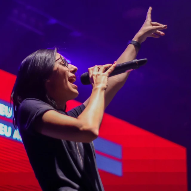 a woman singing into a microphone and holding a mic up in front of her