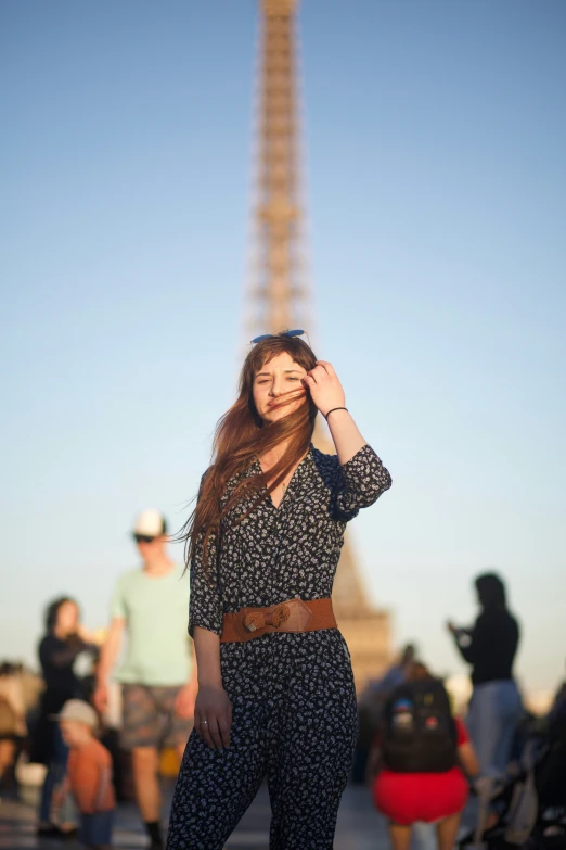 a woman with red hair stands in front of a view of the eiffel tower