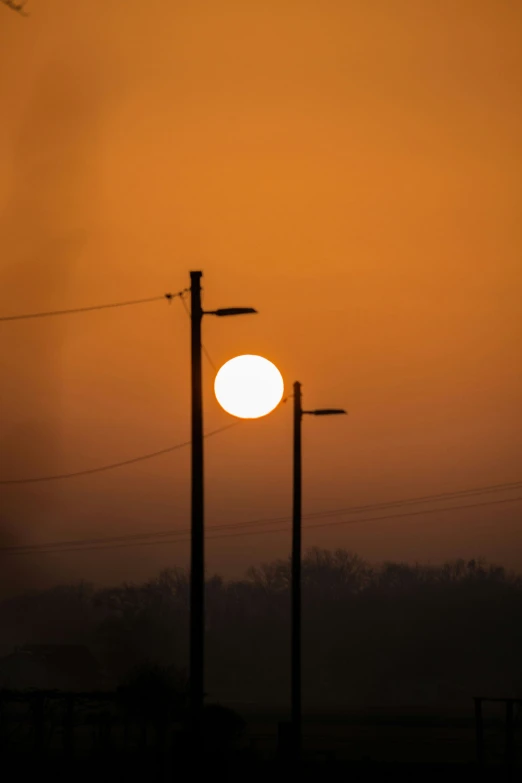 a sun going down behind power lines in the distance